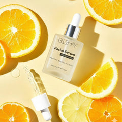 Facial serum bottle with dropper on a yellow background with orange slices