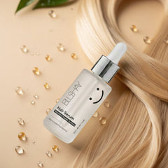 BLS-HAY hair serum bottle with dropper on a beige background with blonde hair and leaves.